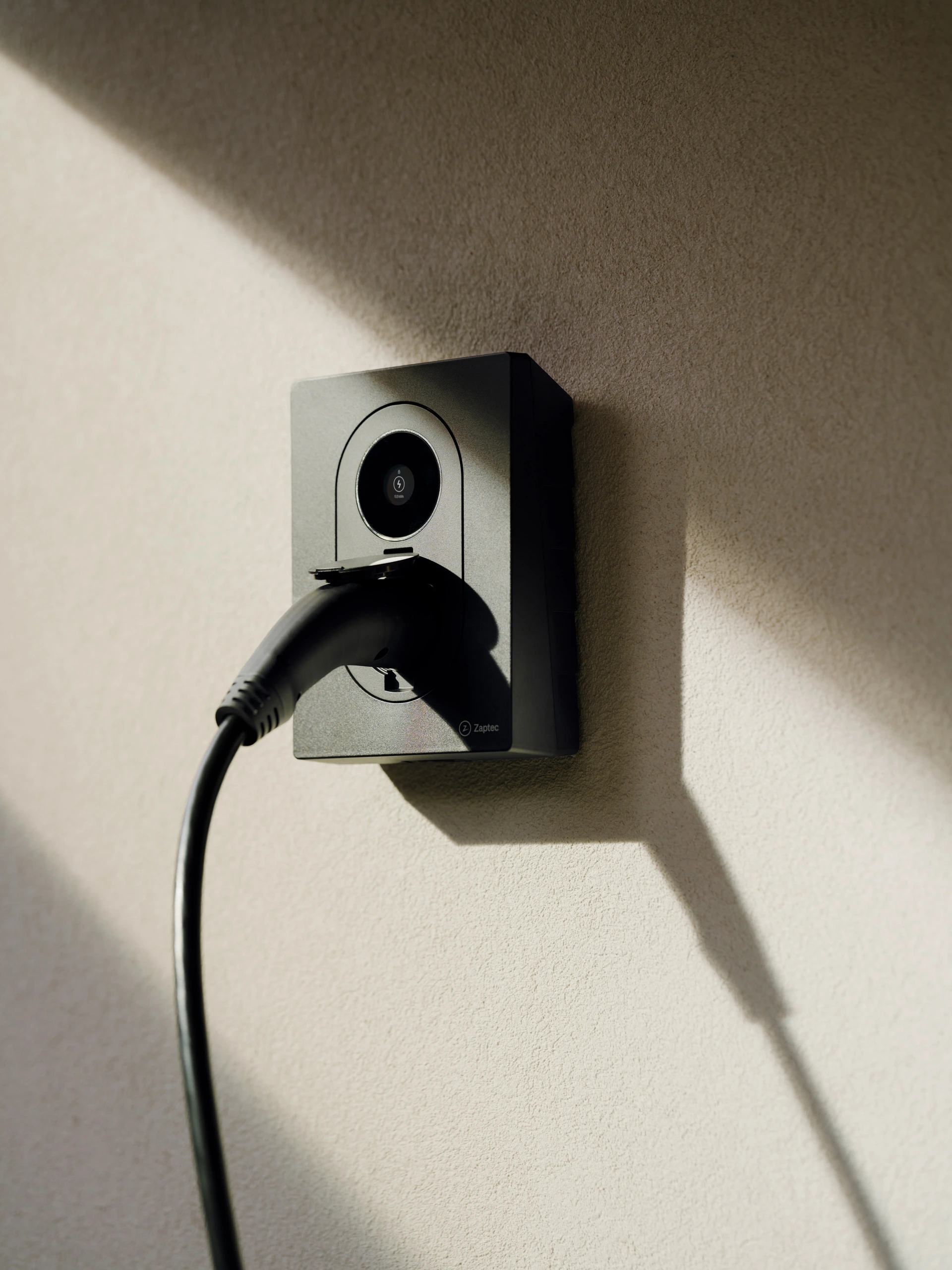 Laadpunt met laadkabel aan een lichte gevel